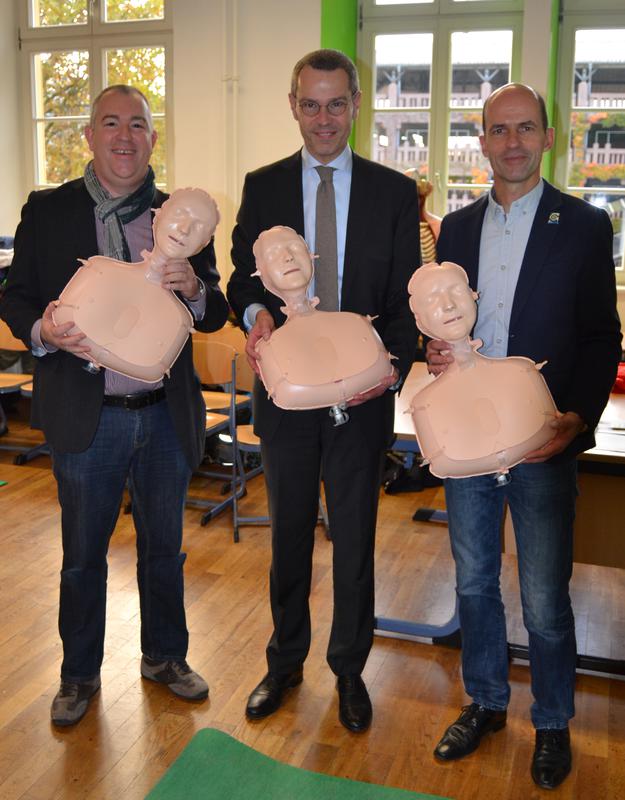 B&uuml;rgermeister und Schuldezernent Dr. Maximilian Ingenthron gemeinsam mit Bernhard Gliwitzky, Mitglied des Exekutivkomitees des German Resuscitation Councils (GRC) (l.) und Andreas Doll, Schulleiter des Otto-Hahn-Gymnasiums (r.) bei der Einf&uuml;hrung des Rean