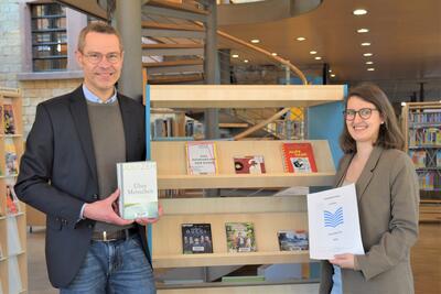 Bild vergr&ouml;&szlig;ern: B&uuml;rgermeister Dr. Maximilian Ingenthron und Bibliotheksleiterin Miriam J&ouml;st mit einigen der im vergangenen Jahr meistgefragten Medien der Stadtbibliothek.