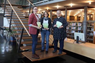 Bild vergr&ouml;&szlig;ern: Beigeordnete Lena D&uuml;rphold (v.l.n.r.) und die Bibliotheksleiterinnen Amelie L&ouml;hlein und Sabine Sch&auml;fer freuen sich auf das Programm der 40. Landauer B&uuml;chereitage.