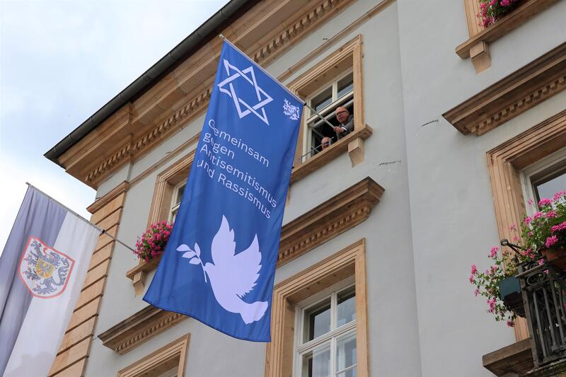 Oberb&uuml;rgermeister Dominik Gei&szlig;ler (r.) und Hausmeister Gernot Cadorin beim H&auml;ngen der Flagge gegen Antisemitismus und Rassismus. 