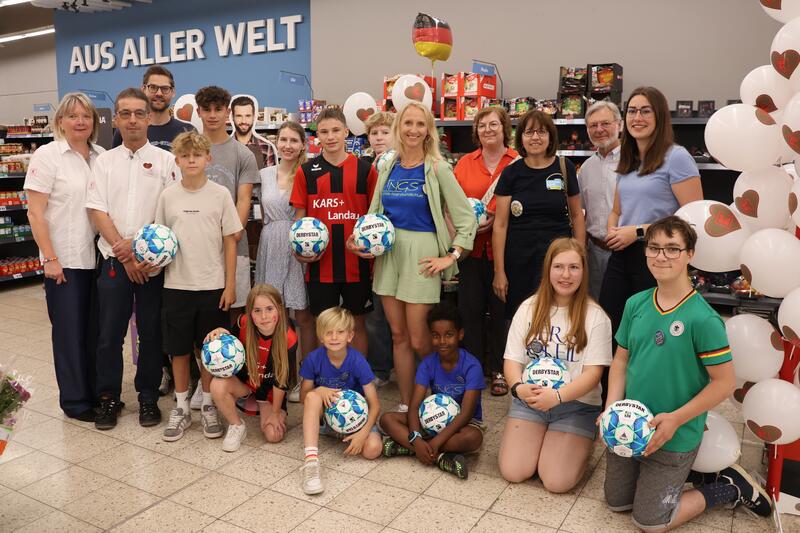 Beigeordnete Lena D&uuml;rphold (1. v. r.)  und Marktleiterin Heike Hohlfeld (1. v. l.) haben die ersten Fu&szlig;b&auml;lle gemeinsam mit Mitgliedern der Fairtrade-Steuerungsgruppe an Vertreterinnen und Vertreter von Thomas-Nast-Grundschule, Otto-Hahn-Gymnasium, Paul-Mo