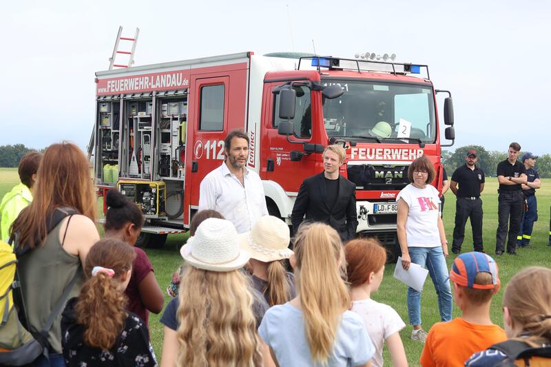 von hinten links nach rechts: Dr. David Els&auml;sser (Umweltamt Stadt Landau), B&uuml;rgermeister Lukas Hartmann, Annette Liebel (Umweltamt Stadt Landau) mit Mitarbeitern der Landauer Feuerwehr und Landauer Sch&uuml;lerinnen und Sch&uuml;ler.