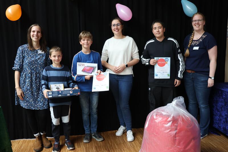 Beigeordnete Lena D&uuml;rphold (3. Von rechts), die Leiterin der Kinder- und Jugendbibliothek Magdalena Schlosser (rechts) und Lena Ferguson vom Team der Stadtbibliothek (links) gemeinsam mit den drei Gewinnern der Lesesommer-Hauptpreise. 