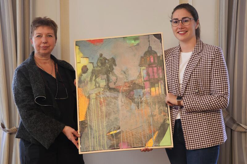 Beigeordnete Lena D&uuml;rphold (rechts) hat das Gem&auml;lde von der K&uuml;nstlerin Olga David entgegengenommen. 