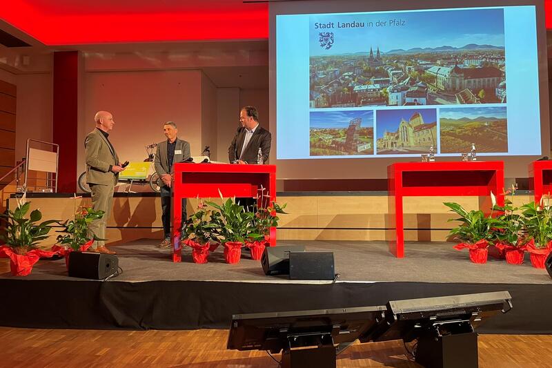 &Uuml;bergabe des Staffelstabs zur Fahrradkommunalkonferenz (v.l.n.r. Bernt H&uuml;sken, Fachbereichsleiter Verkehr bei der Region Hannover, Ralf Bernhard, Abteilungsleitung Verkehr bei der Stadt Landau und Roman Willweber vom Bundesamt f&uuml;r Logistik und Mobilit&auml;t.