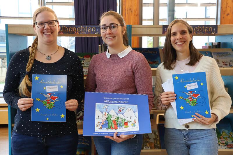 Die Vorweihnachtszeit kann kommen: Beigeordnete Lena D&uuml;rphold (Mitte) und die Bibliotheksmitarbeiterinnen Magdalena Schlosser (links) und Lena Ferguson mit den Adventskalendern.