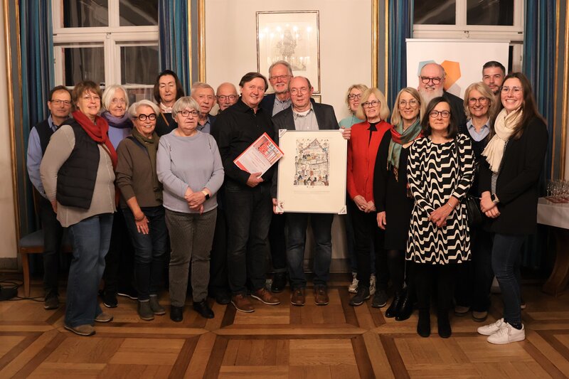 Bei der Verleihung des Ehrenamtspreises an Seniorenb&uuml;ro-Ehrenamtsb&ouml;rse Landau: Beigeordnete Lena D&uuml;rphold (rechts), Laudator Hans-Dieter Schlimmer (hintere Reihe, 6. v. l.), davor die Vereinsvorsitzenden Uli M&uuml;ller-Weissner (mit Bild) und Ulrich Teichmann