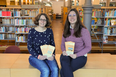 Bild vergr&ouml;&szlig;ern: Beigeordnete Lena D&uuml;rphold (rechts) und Co-Bibliotheksleiterin Amelie L&ouml;hlein freuen sich auf die Veranstaltungen im ersten Halbjahr 2026 in der Stadtbibliothek.