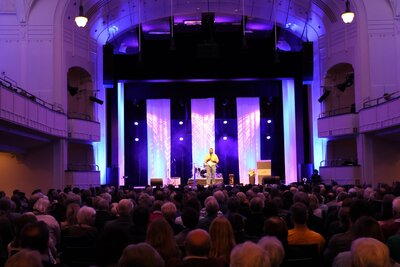 Bild vergr&ouml;&szlig;ern: Die Stadt Landau begr&uuml;&szlig;t das neue Jahr traditionell mit ihrem Neujahrsempfang in der Jugendstil-Festhalle - hier 2025 der Auftritt von Poetry-Slammer Anuraj Sri Rajarajendran.