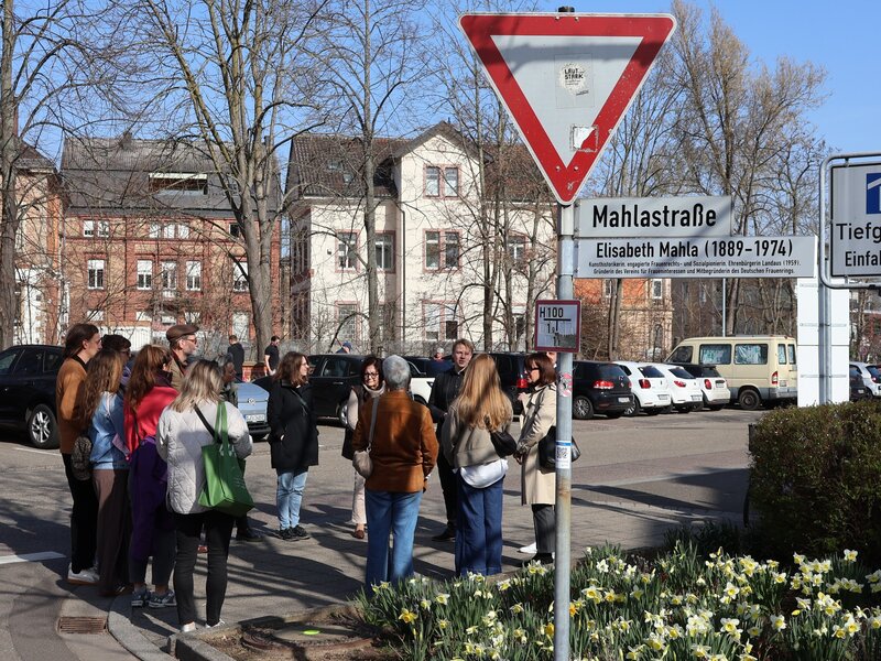 Gemeinsam mit Interessierten enth&uuml;llen B&uuml;rgermeister Lukas Hartmann, Gleichstellungsbeauftragte Laura Hess und Stadtarchivarin Christine Kohl-Langer ein neues Erg&auml;nzungsschild f&uuml;r die Mahlastra&szlig;e. 