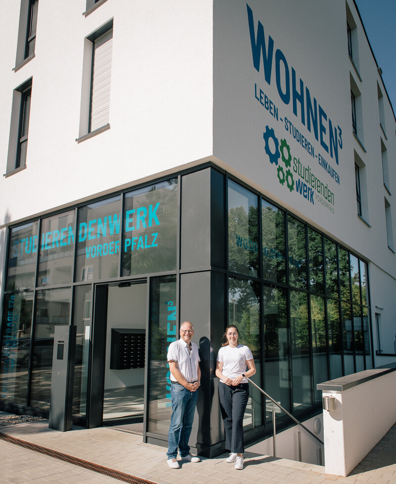 Landaus Beigeordnete Lena D&uuml;rphold (rechts) und Andreas Sch&uuml;lke, Gesch&auml;ftsf&uuml;hrer des Studierendenwerks Vorderpfalz, vor dem Wohnheim in der Annweilerstra&szlig;e: K&uuml;nftig k&ouml;nnen dort freie Wohnheimpl&auml;tze auch an Auszubildende vermietet werden. 