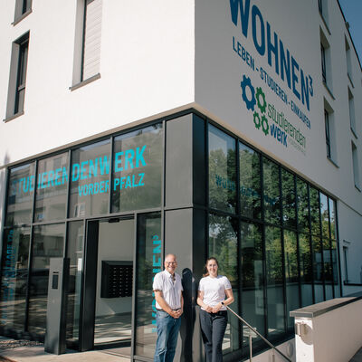 Bild vergr&ouml;&szlig;ern: Landaus Beigeordnete Lena D&uuml;rphold (rechts) und Andreas Sch&uuml;lke, Gesch&auml;ftsf&uuml;hrer des Studierendenwerks Vorderpfalz, vor dem Wohnheim in der Annweilerstra&szlig;e: K&uuml;nftig k&ouml;nnen dort freie Wohnheimpl&auml;tze auch an Auszubildende vermietet werden.