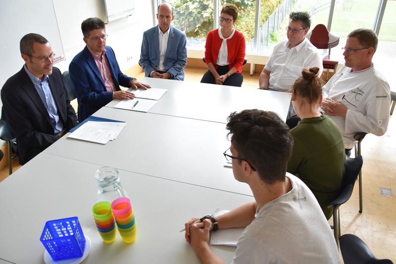 Einmal zur&uuml;ck in die Schulzeit versetzt f&uuml;hlten sich B&uuml;rgermeister Dr. Maximilian Ingenthron, Schulamtsleiter Ralf M&uuml;ller, Caterer Ren&eacute; Rebmann und Vertreterinnen und Vertreter der Schule sowie der Presse beim Vor-Ort-Termin in der Mensa des Otto-Hahn-Gym