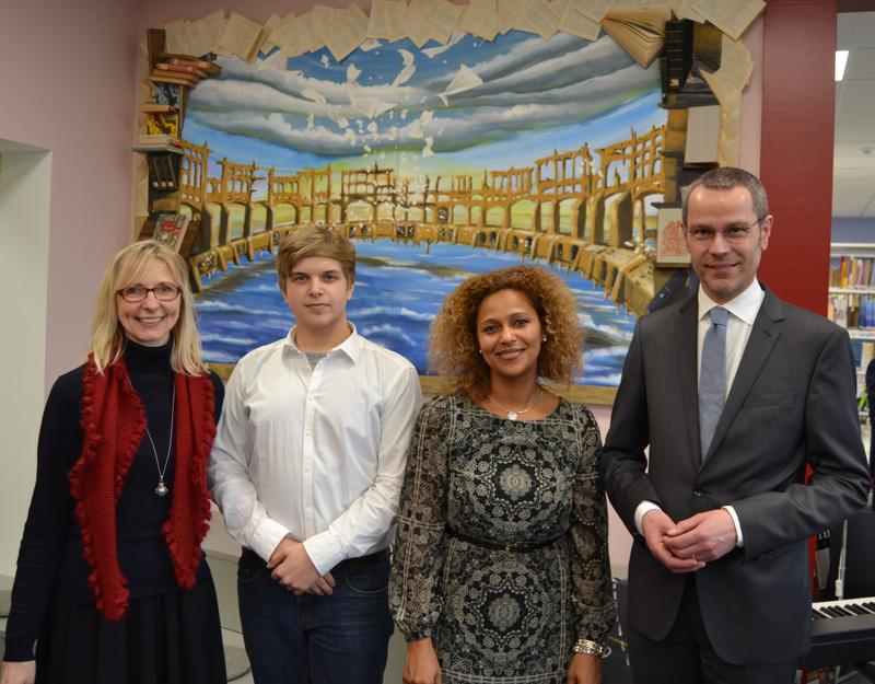 Literatur trifft Kunst! B&uuml;rgermeister und Schuldezernent Dr. Maximilian Ingenthron (r.) gemeinsam mit Schulleiterin Dagmar Linnert (l.), Bibliotheksleiterin Yasmine Kourouma und Valentin Zimnol, dem K&uuml;nstler des Werks im Hintergrund, das der Sch&uuml;ler eigen