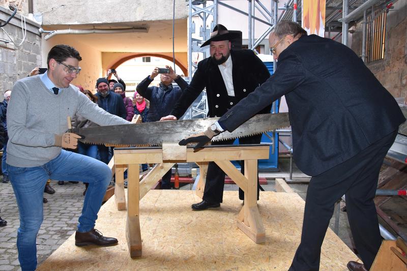Symbolischer Akt: OB Thomas Hirsch (l.) und Genossenschaftsvorsitzender Dr. Michael Zumpe s&auml;gten zu Sanierungsbeginn des Hauses zum Maulbeerbaum den ersten von vielen zu erneuernden Balken durch. 
