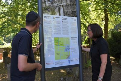 Bild vergr&ouml;&szlig;ern: B&uuml;rgermeister Dr. Maximilian Ingenthron und Stadtarchivarin Christine Kohl-Langer begutachten die neue Hinweistafel am j&uuml;dischen Friedhof in Landau.