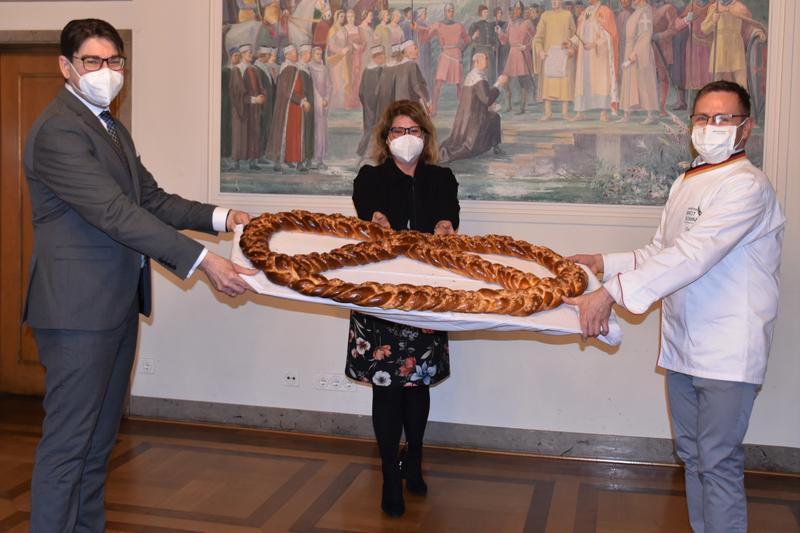 B&auml;ckermeister Becker (r.) &uuml;berreichte Landaus OB Hirsch auch in diesem Jahr eine riesige Neujahrsbrezel als Gl&uuml;cksbringer. Gleichstellungsbeauftragte Evi Julier brachte die Brezel anschlie&szlig;end ins Frauenhaus. 