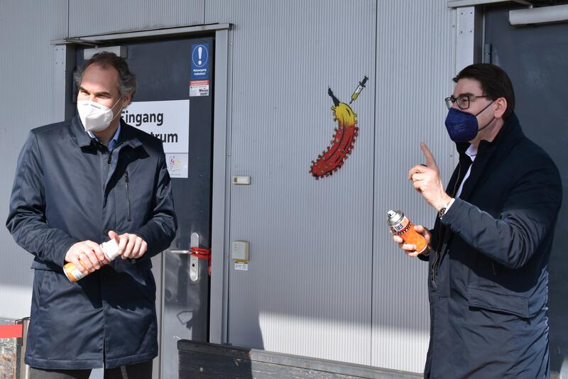 Landrat Seefeldt (l.) und OB Hirsch bei der Kunstaktion am Impfzentrum LD/S&Uuml;W. 