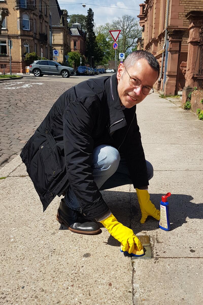 Landaus B&uuml;rgermeister Dr. Maximilian Ingenthron beim Reinigen eines Stolpersteins in der Langstra&szlig;e. 