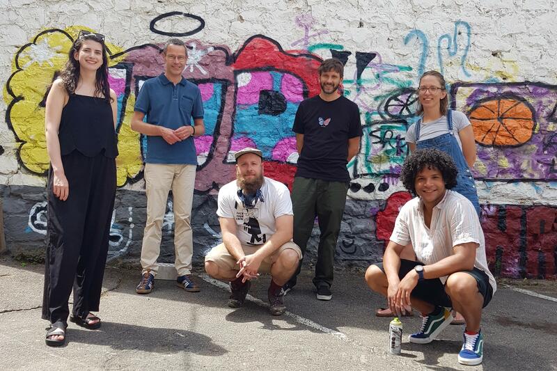 Kulturdezernent Dr. Maximilian Ingenthron (2.v.l.) mit den Akteurinnen und Akteuren der Workshopreihe &raquo;Street Art meets Lost Place&laquo; in den Uferschen H&ouml;fen. K&uuml;nftig soll der Kulturbeirat eine neue Plattform des Austauschs f&uuml;r K&uuml;nstlerinnen und K&uuml;nstler bie